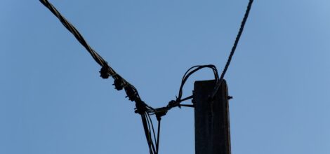 a telephone pole with wires and a blue sky in the background
