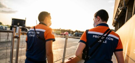 man in blue and orange adidas t-shirt and blue shorts with black backpack walking on near near on on