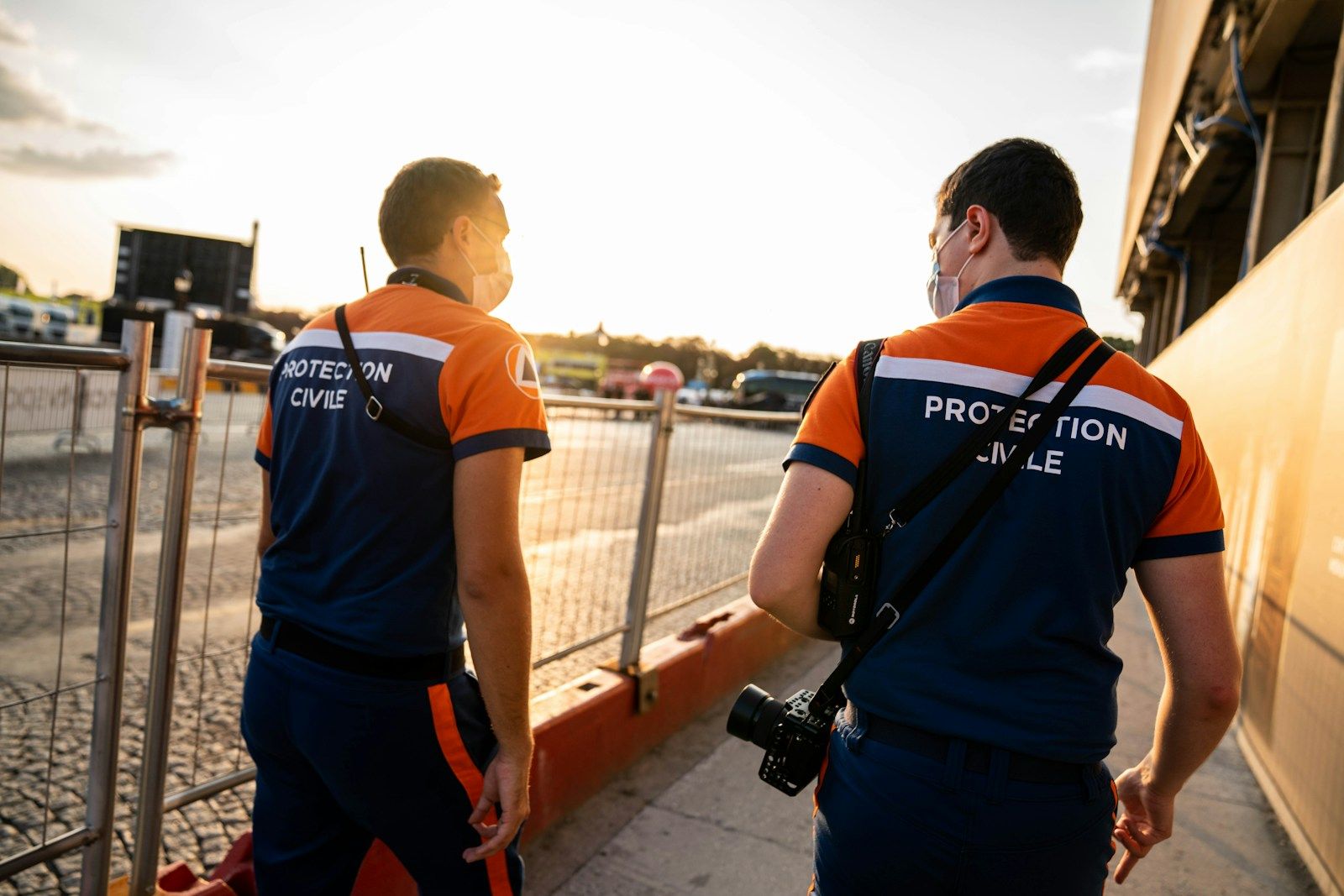 man in blue and orange adidas t-shirt and blue shorts with black backpack walking on near near on on